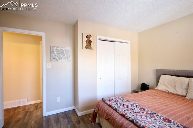 bedroom with dark wood-type flooring, a textured ceiling, and a closet