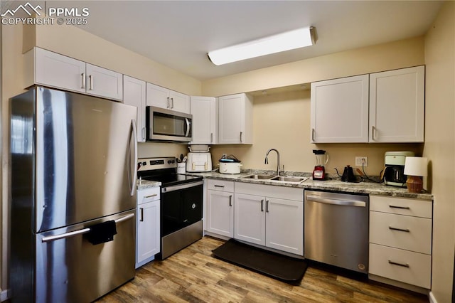 kitchen featuring light stone countertops, sink, stainless steel appliances, and white cabinetry