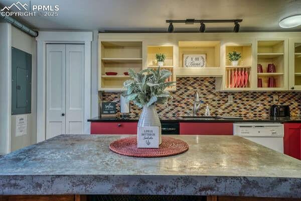 kitchen featuring tasteful backsplash, dishwasher, a kitchen island, electric panel, and sink