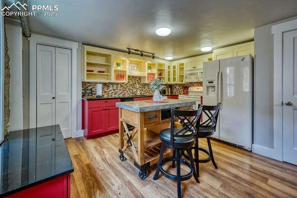 kitchen featuring backsplash, a center island, white appliances, and light hardwood / wood-style flooring