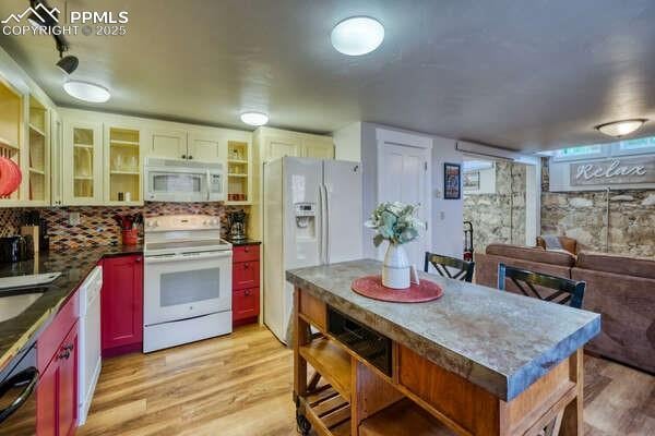 kitchen featuring decorative backsplash, light hardwood / wood-style flooring, white cabinets, and white appliances