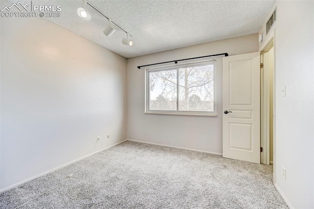 unfurnished room featuring light carpet, track lighting, and a textured ceiling