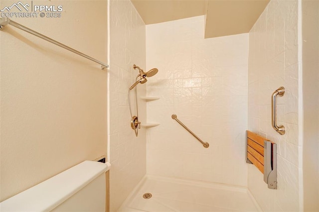 bathroom with a tile shower and toilet