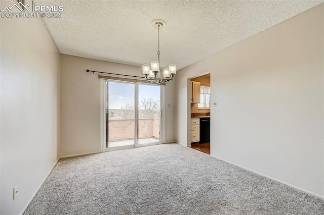 spare room with an inviting chandelier, carpet floors, and a textured ceiling