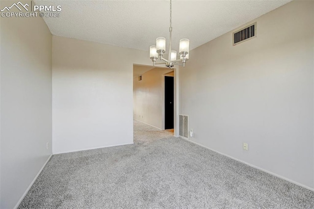 carpeted spare room with a chandelier and a textured ceiling