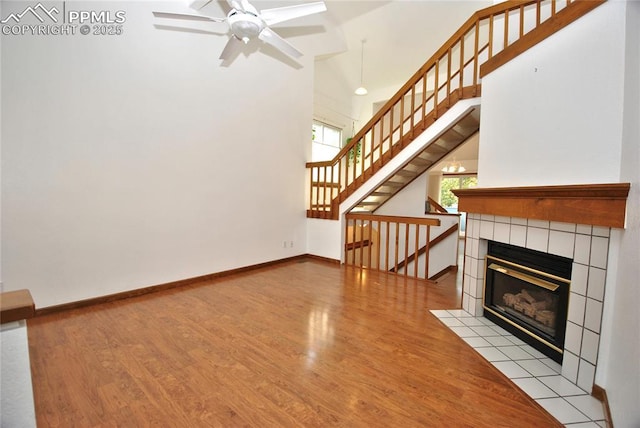 unfurnished living room featuring light hardwood / wood-style floors, a tile fireplace, and ceiling fan