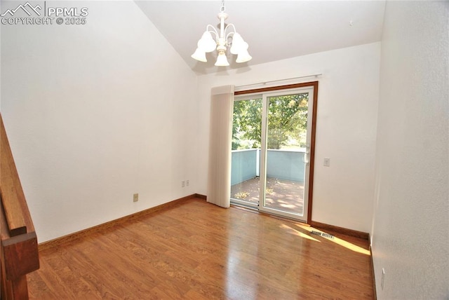 spare room with a chandelier, lofted ceiling, and hardwood / wood-style flooring