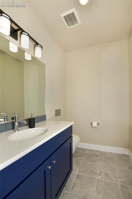 bathroom with toilet, vanity, and tile patterned flooring