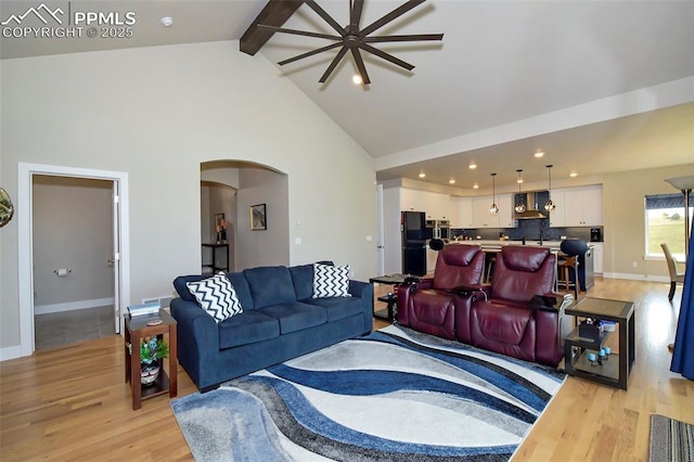 living room featuring light wood-type flooring, sink, high vaulted ceiling, and beamed ceiling