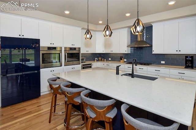 kitchen featuring a center island with sink, white cabinetry, and black fridge