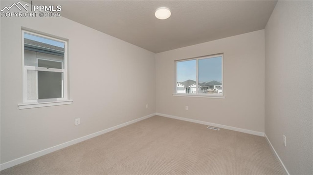 empty room featuring carpet, visible vents, and baseboards