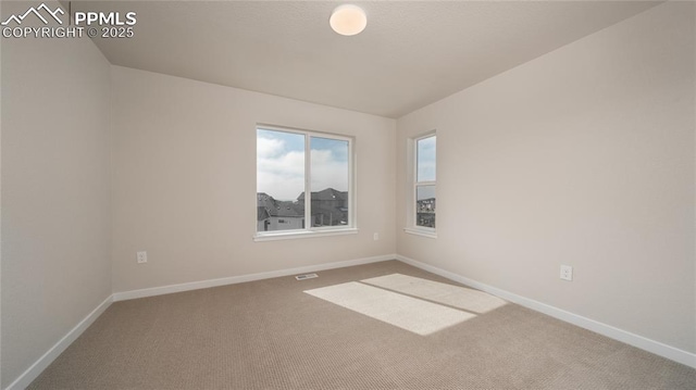 spare room with carpet flooring, visible vents, and baseboards