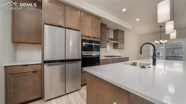 kitchen featuring wall chimney exhaust hood, freestanding refrigerator, a sink, black stovetop, and backsplash