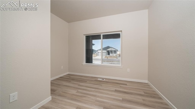 unfurnished room featuring baseboards, visible vents, and light wood-style floors