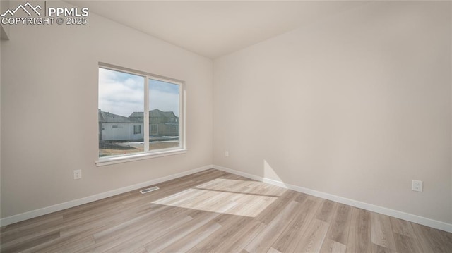 empty room featuring light wood-type flooring, visible vents, and baseboards