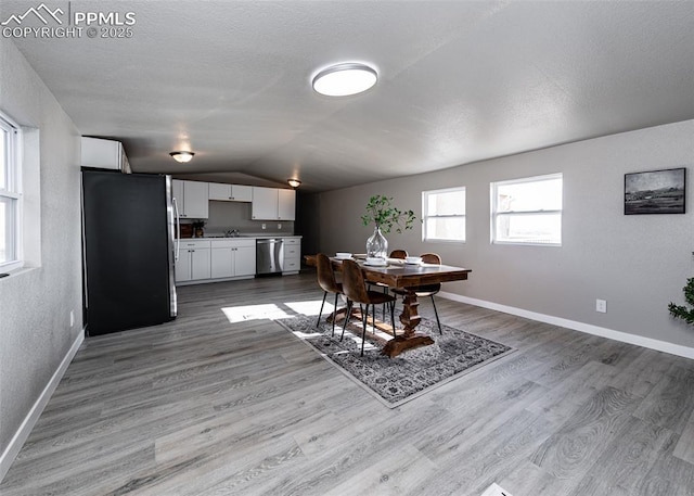 dining space featuring lofted ceiling and light hardwood / wood-style flooring