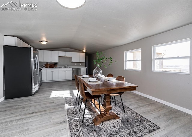 dining area with lofted ceiling and light hardwood / wood-style flooring