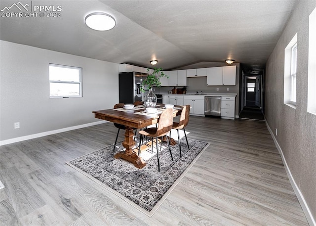 dining space featuring vaulted ceiling, sink, and light hardwood / wood-style floors