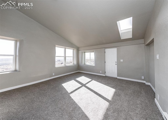 spare room with vaulted ceiling with skylight and dark carpet