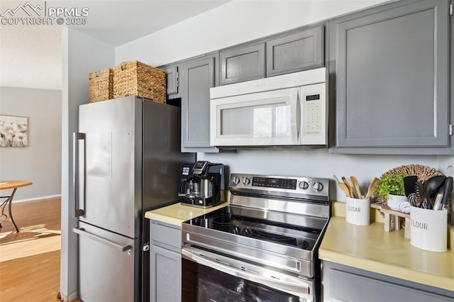 kitchen with gray cabinets, wood-type flooring, and appliances with stainless steel finishes