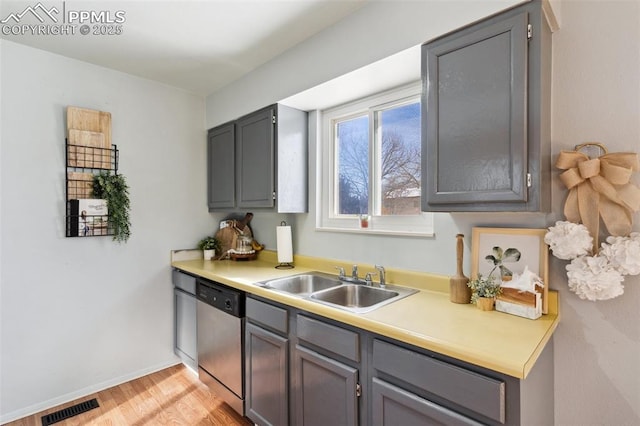 kitchen featuring light hardwood / wood-style flooring, sink, stainless steel dishwasher, and gray cabinetry