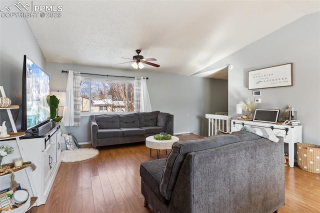 living room with hardwood / wood-style flooring, vaulted ceiling, a textured ceiling, and ceiling fan