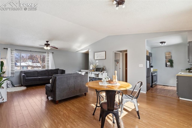 dining room featuring vaulted ceiling, hardwood / wood-style floors, a textured ceiling, and ceiling fan