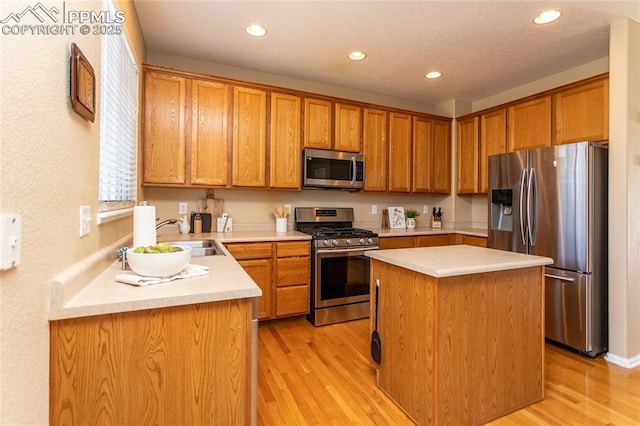 kitchen featuring appliances with stainless steel finishes, sink, light hardwood / wood-style floors, and a center island