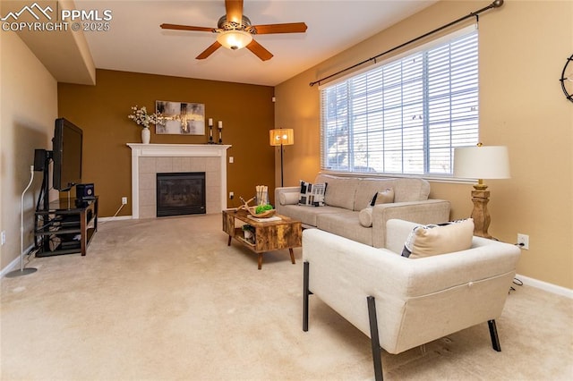 carpeted living room with ceiling fan and a tile fireplace