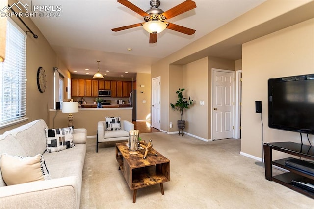 living room featuring ceiling fan, light colored carpet, and plenty of natural light