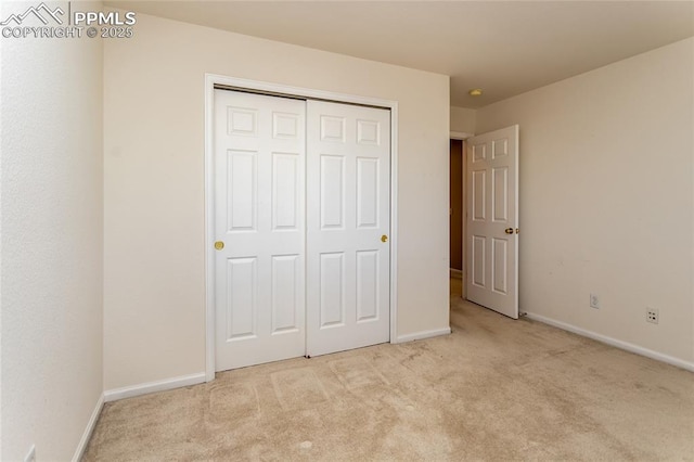 unfurnished bedroom featuring light carpet and a closet