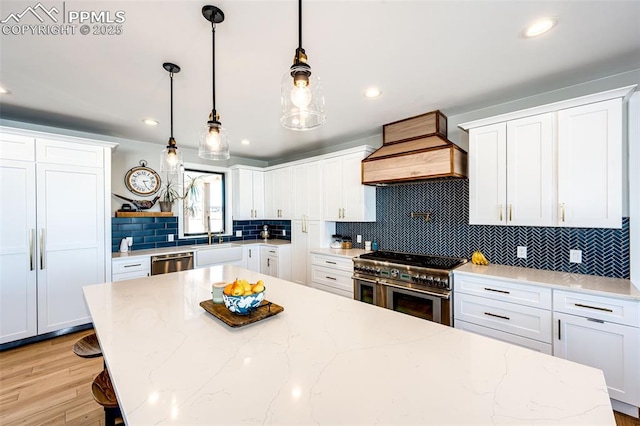 kitchen featuring white cabinetry, stainless steel appliances, and custom range hood