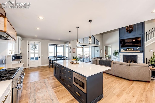 kitchen with white cabinetry, light hardwood / wood-style flooring, hanging light fixtures, and a center island