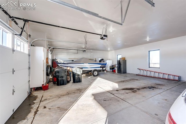 garage with stainless steel refrigerator and a garage door opener