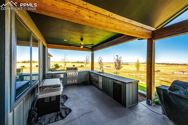 view of patio / terrace featuring a rural view, a grill, an outdoor kitchen, sink, and ceiling fan