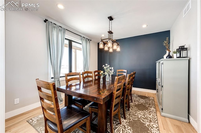 dining space featuring light hardwood / wood-style flooring and a chandelier