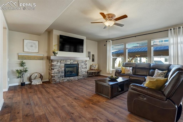 living area with ceiling fan, dark wood-style flooring, a fireplace, and baseboards