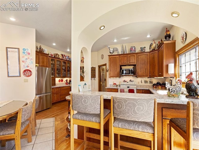 kitchen with stainless steel appliances, kitchen peninsula, and light hardwood / wood-style floors