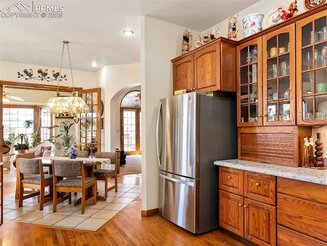 kitchen featuring light stone counters, hanging light fixtures, plenty of natural light, and stainless steel refrigerator