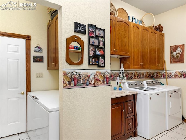 clothes washing area with cabinets, independent washer and dryer, and light tile patterned flooring