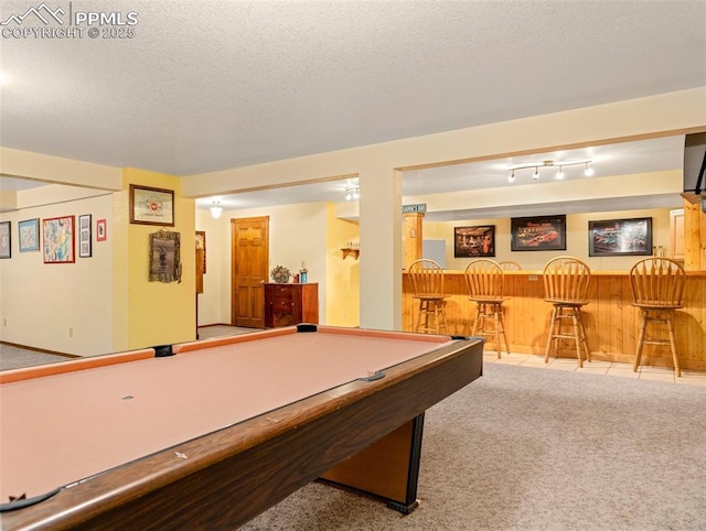 game room featuring bar area, light carpet, and a textured ceiling