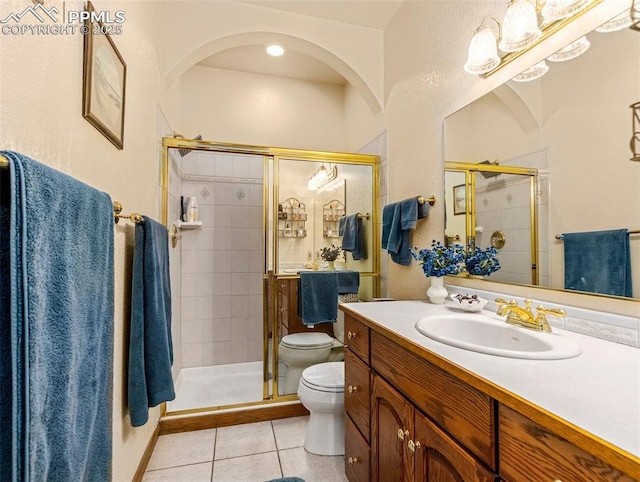 bathroom with tile patterned floors, toilet, a shower with door, and vanity