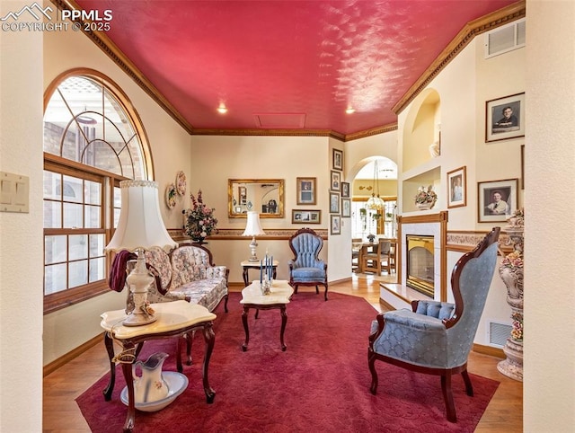 sitting room with crown molding, a high end fireplace, and wood-type flooring