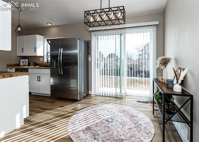 kitchen with decorative light fixtures, stainless steel fridge with ice dispenser, and white cabinetry