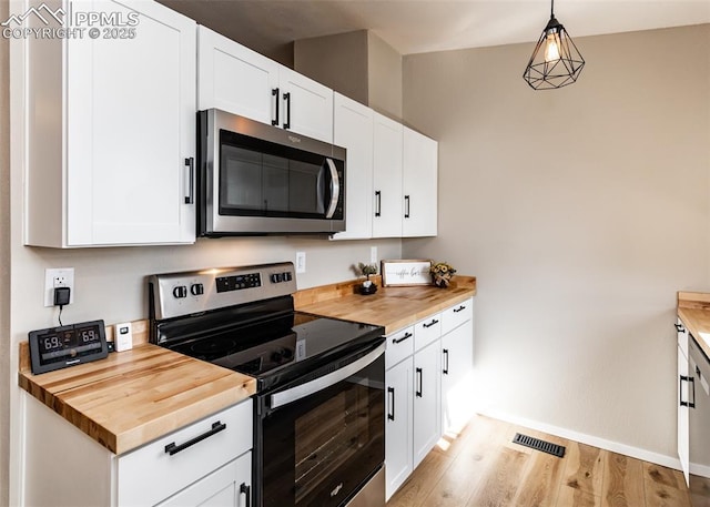 kitchen with decorative light fixtures, white cabinets, appliances with stainless steel finishes, and wooden counters