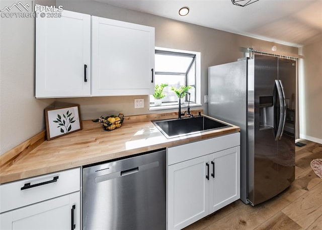 kitchen featuring hardwood / wood-style floors, appliances with stainless steel finishes, white cabinetry, and sink