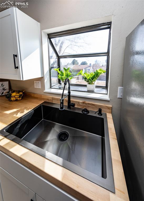 kitchen with white cabinetry, wooden counters, and sink