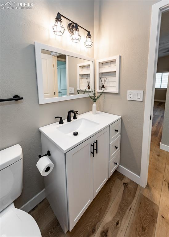 bathroom with toilet, hardwood / wood-style flooring, and vanity