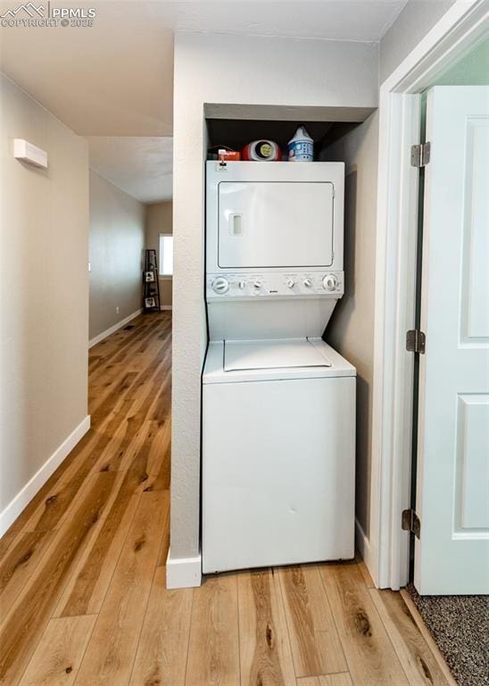 laundry room featuring stacked washer / drying machine and hardwood / wood-style flooring