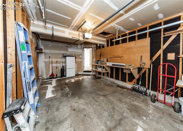 garage featuring white fridge, a garage door opener, and a workshop area